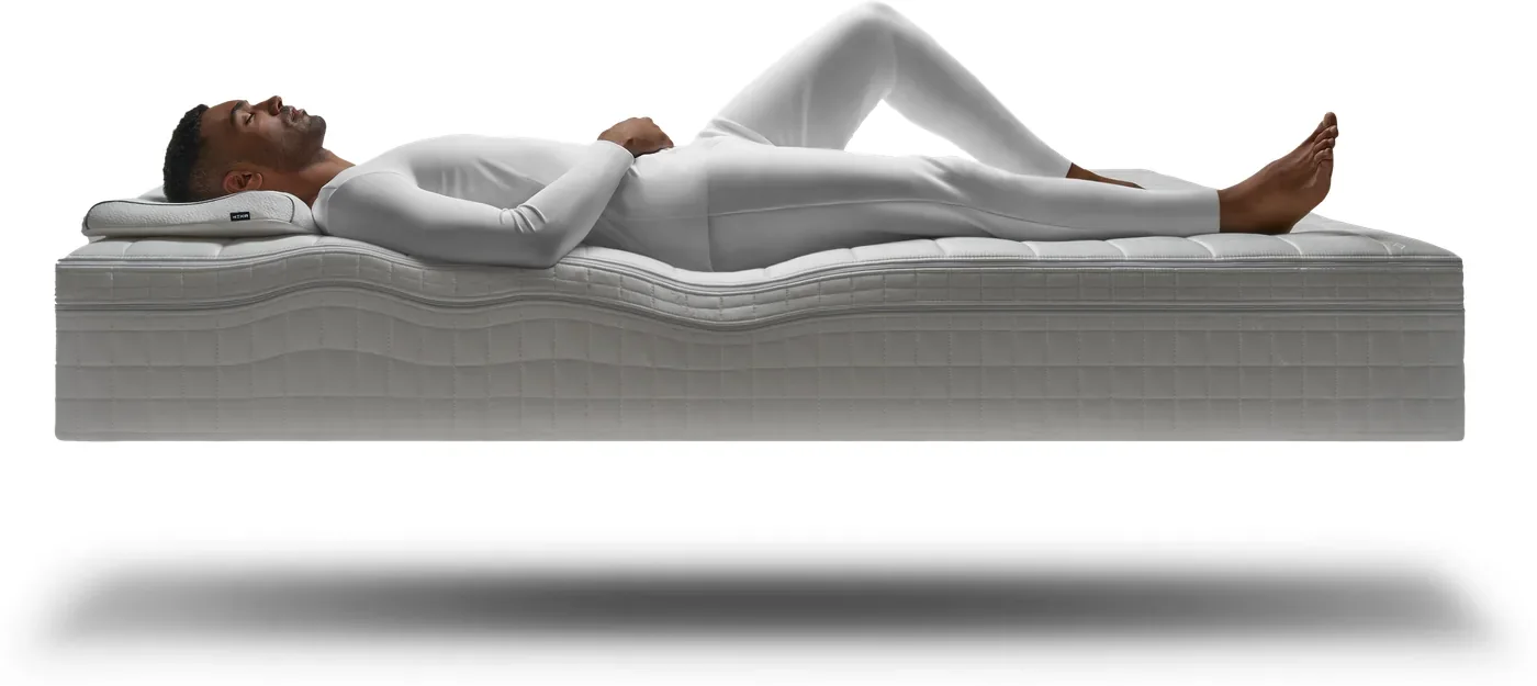 A person lying on their back on the HEKA AI Mattress, the surface rising to fill the lower back