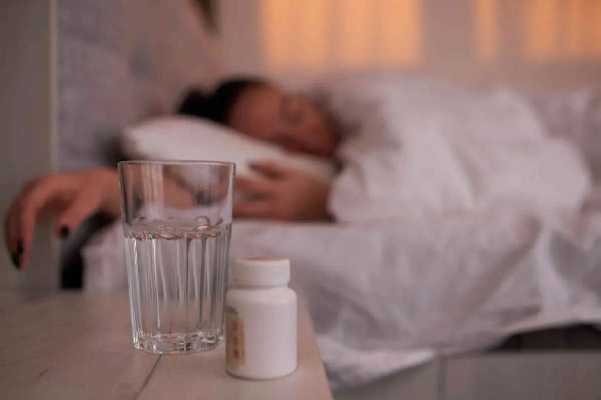 Lọ thuốc và cốc nước đặt cạnh giường ngủ