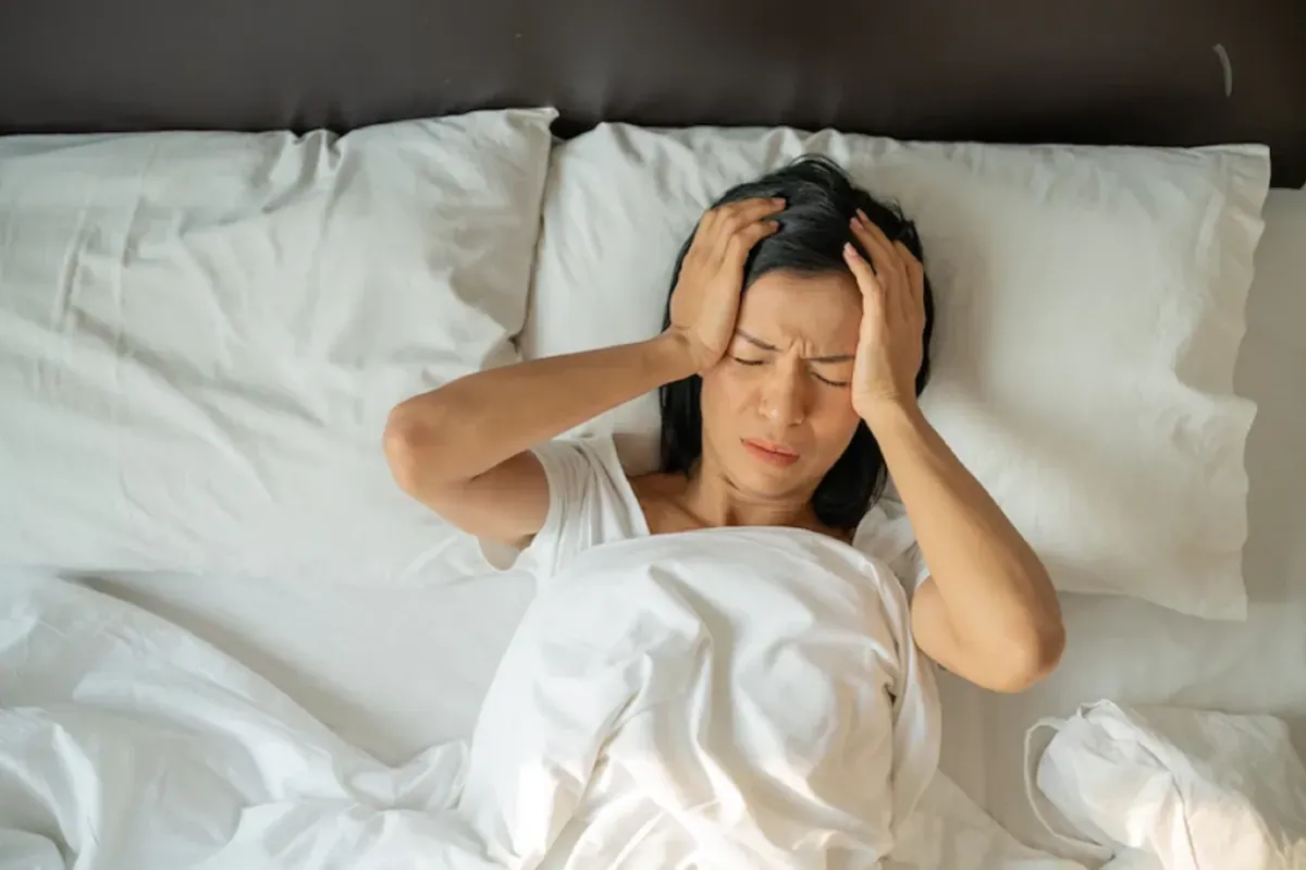 Người phụ nữ ôm đầu căng thẳng trên giường vì khó ngủ