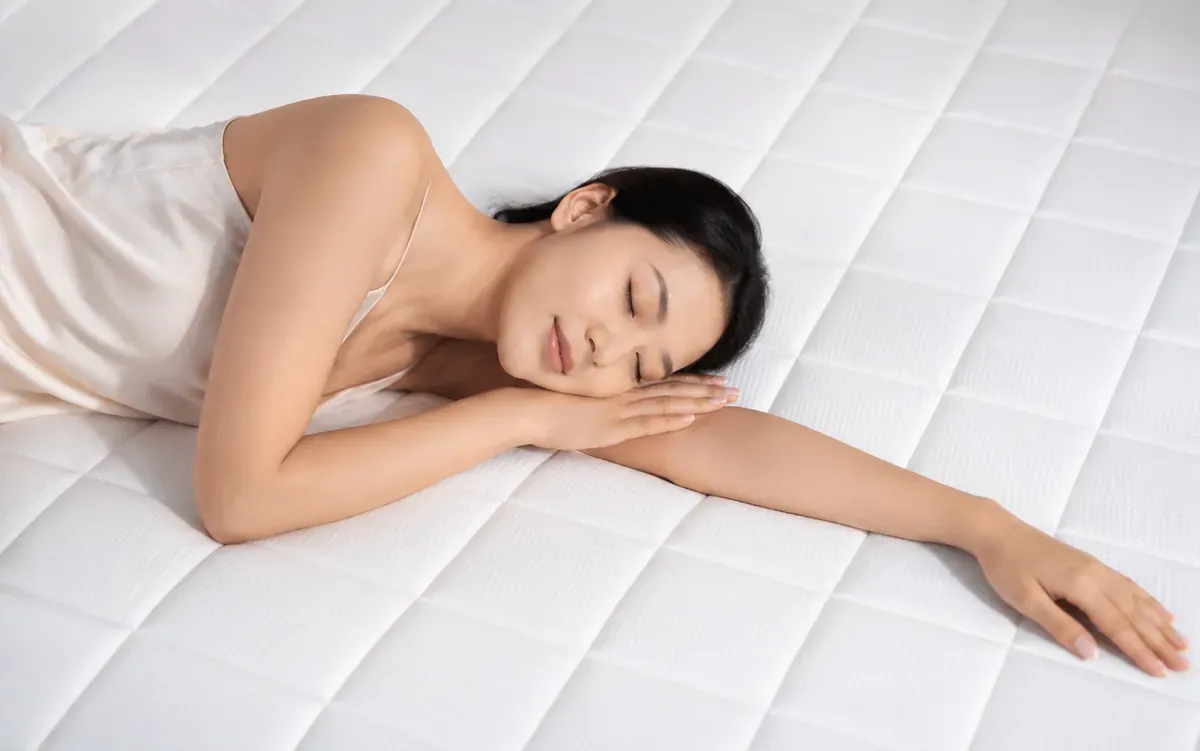 Cô gái nằm nghiêng ngủ ngon trên mặt nệm trắng chần ô vuông