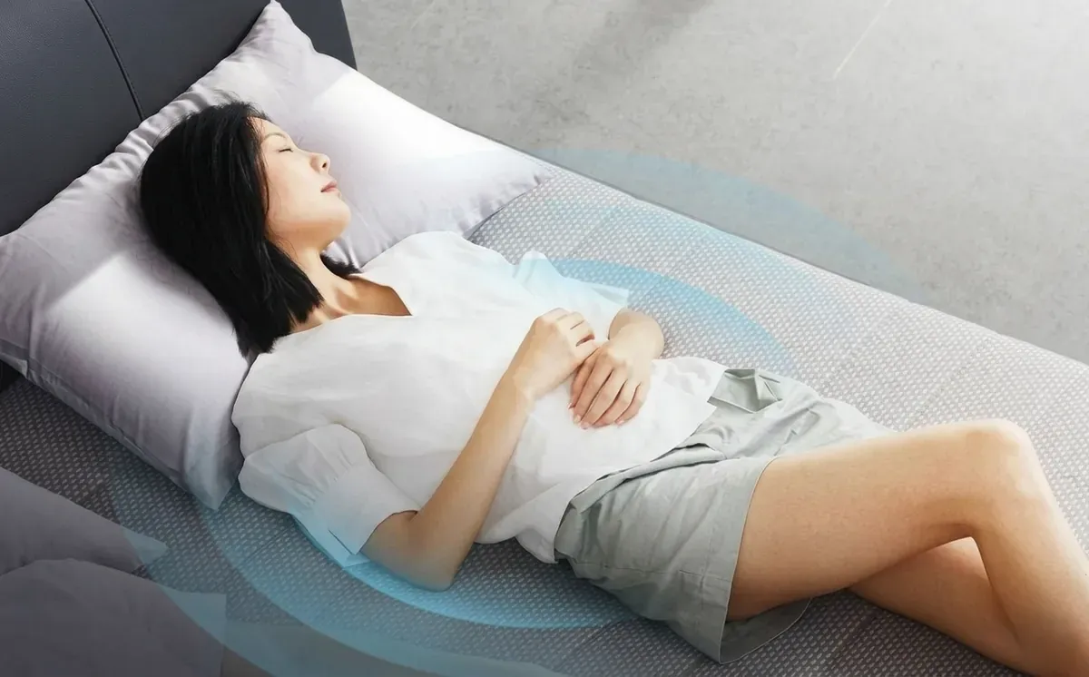 Người phụ nữ nằm ngửa trên nệm, xung quanh là vòng sóng minh họa cảm biến